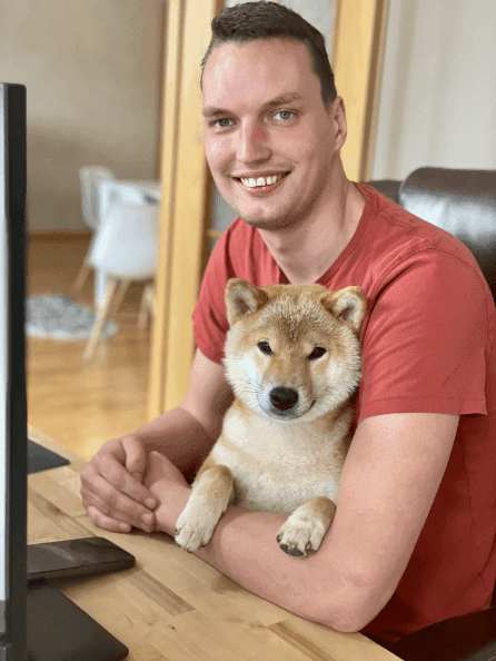 A programmer behind the computer with a dog in his lap